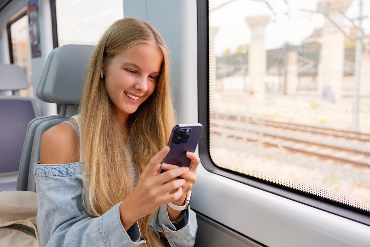 Chica usando iPhone en un tren