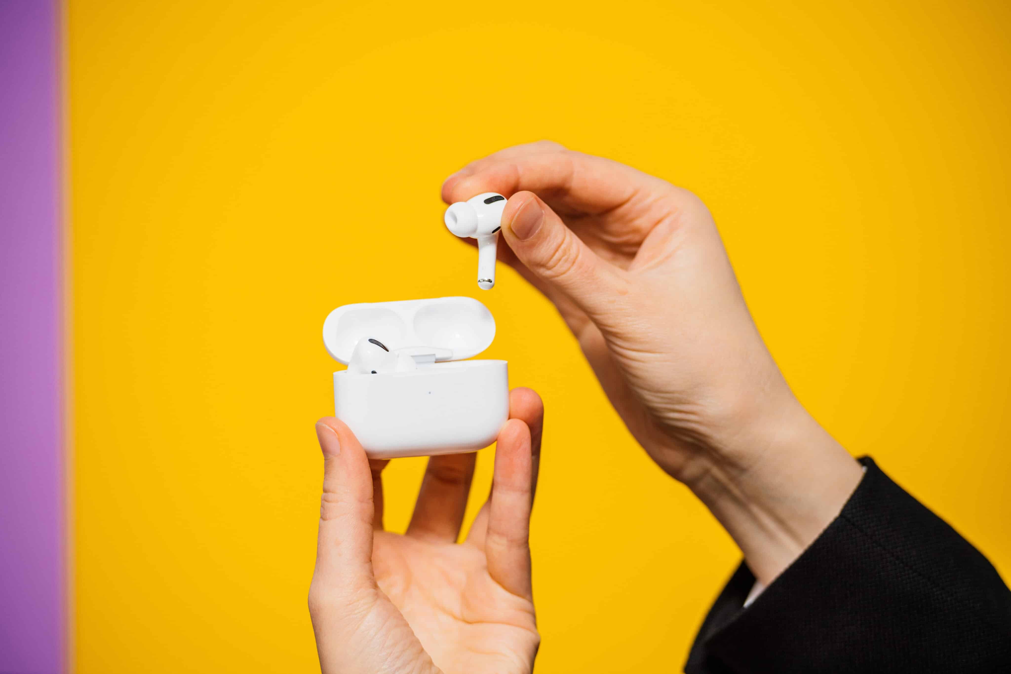 AirPods Pro en manos sobre un fondo amarillo