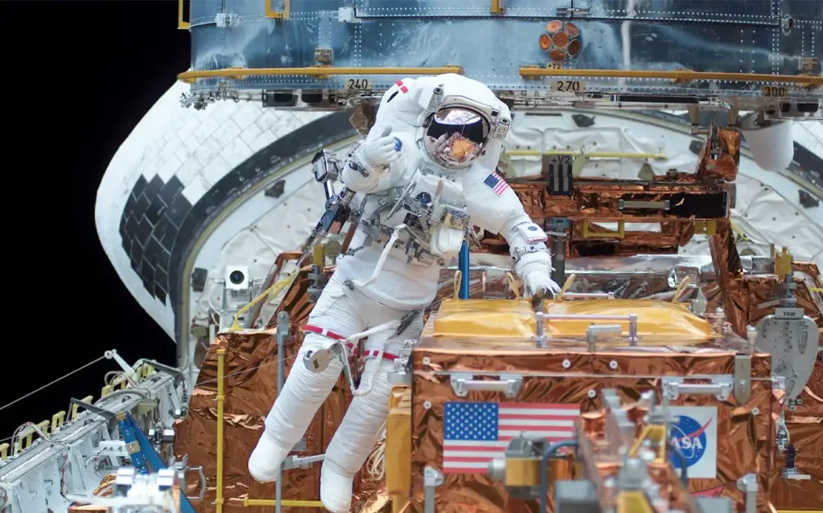 El astronauta James H. Newman, especialista de la misión, se mueve en la bahía de carga del transbordador espacial Columbia mientras trabaja en conjunto con el astronauta Michael J. Massimino, especialista de la misión, durante el segundo día de actividad extravehicular (EVA) de la misión STS-109 / NASA, iPhone