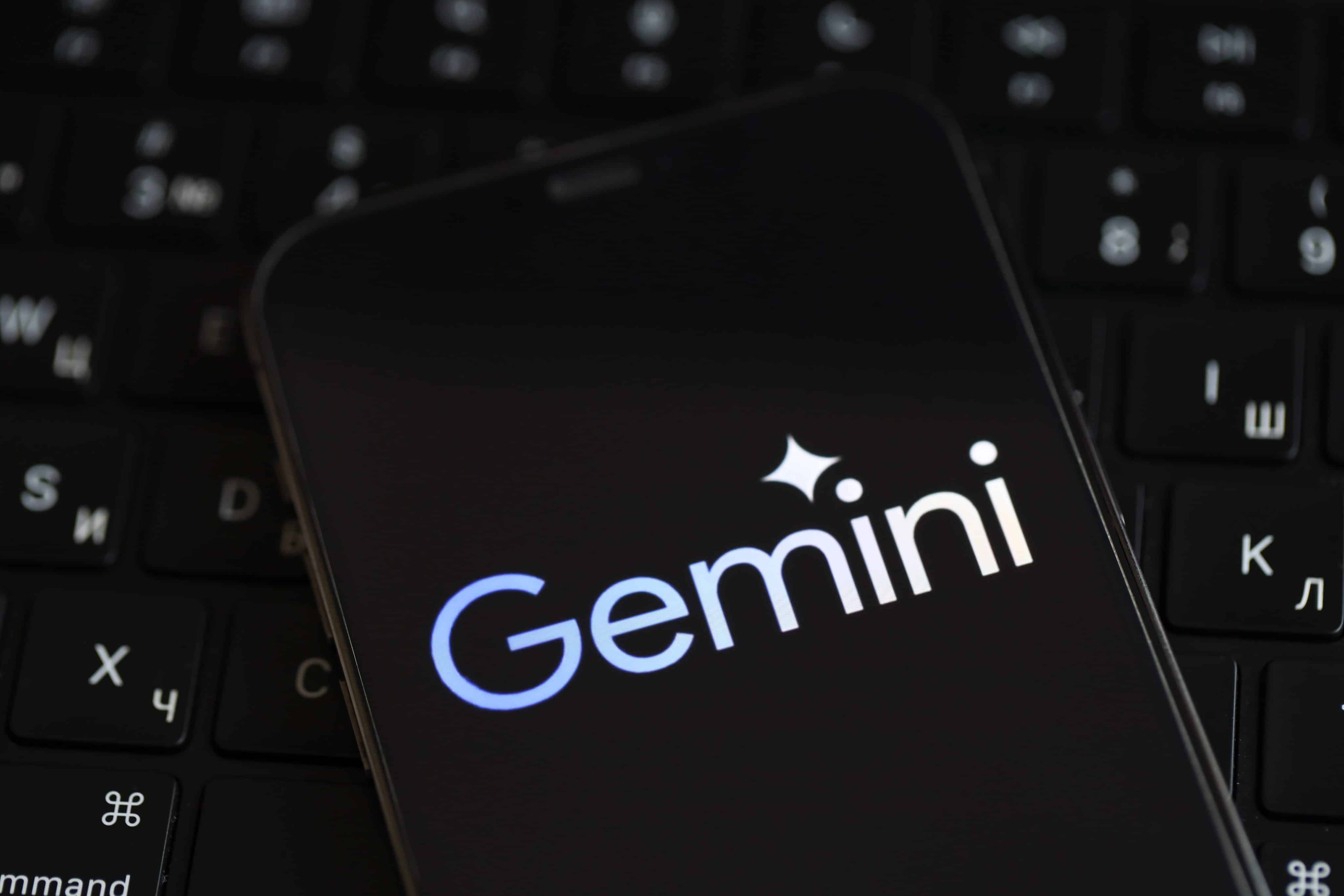 Teléfono encima de una computadora con el logo de Google Gemini