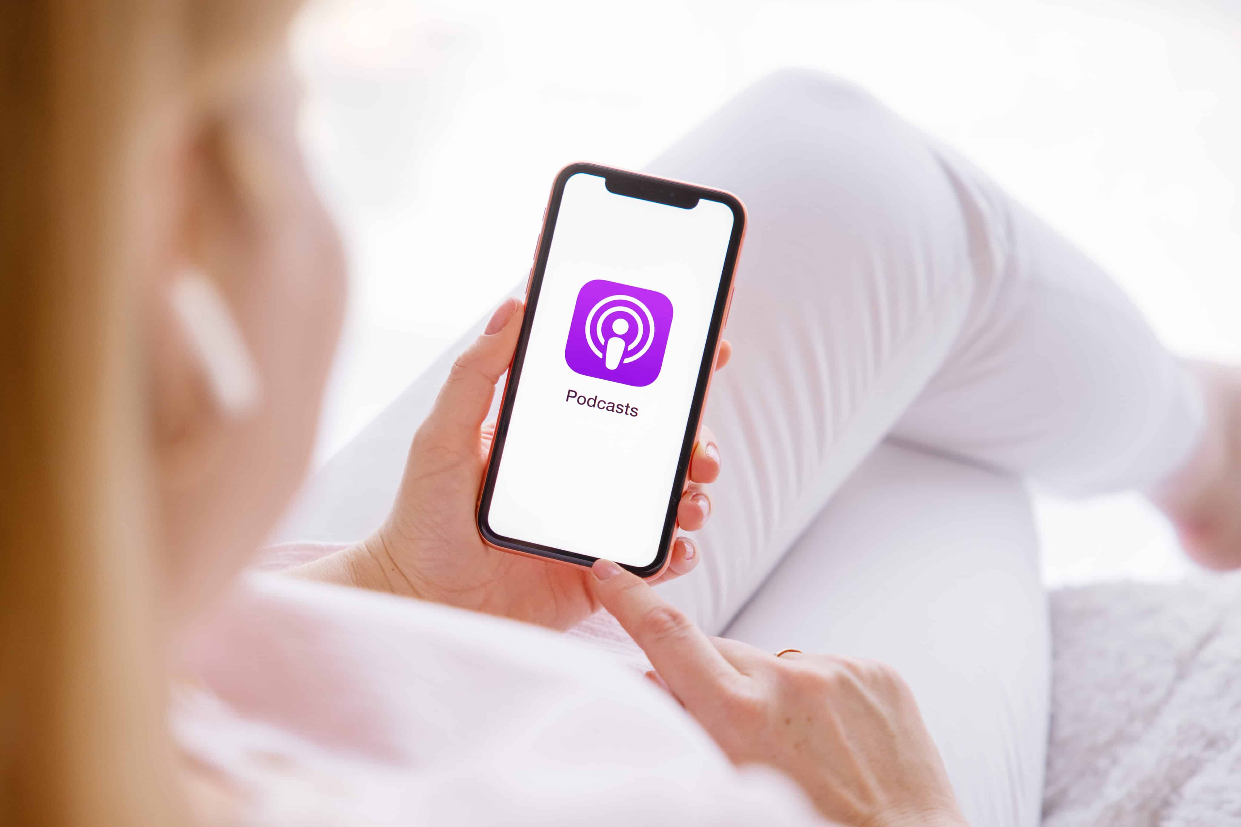 Ícono de la aplicación Podcasts en la pantalla del iPhone sostenido por una mujer