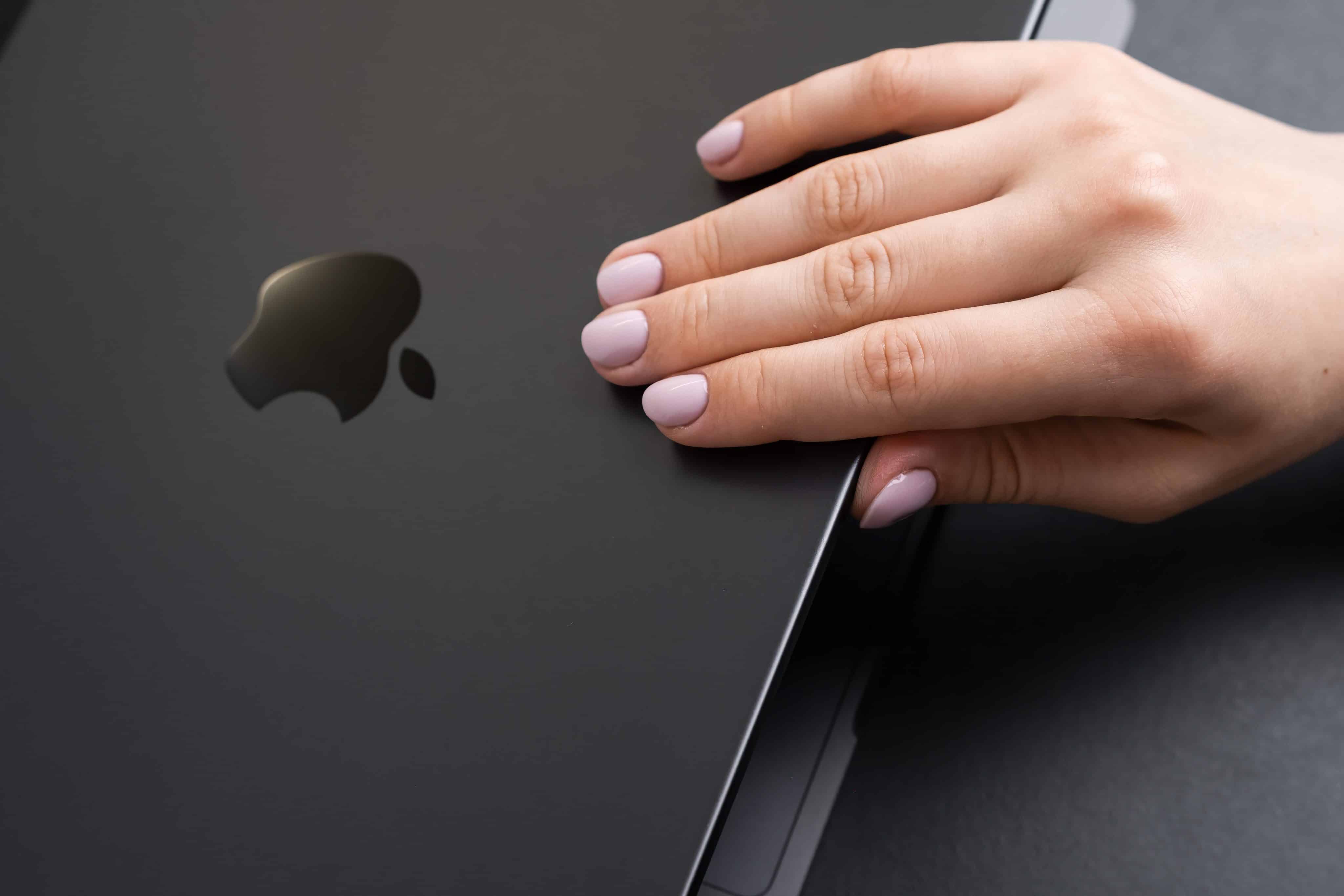 Primer plano de la mano de una mujer abriendo la tapa de una MacBook Pro