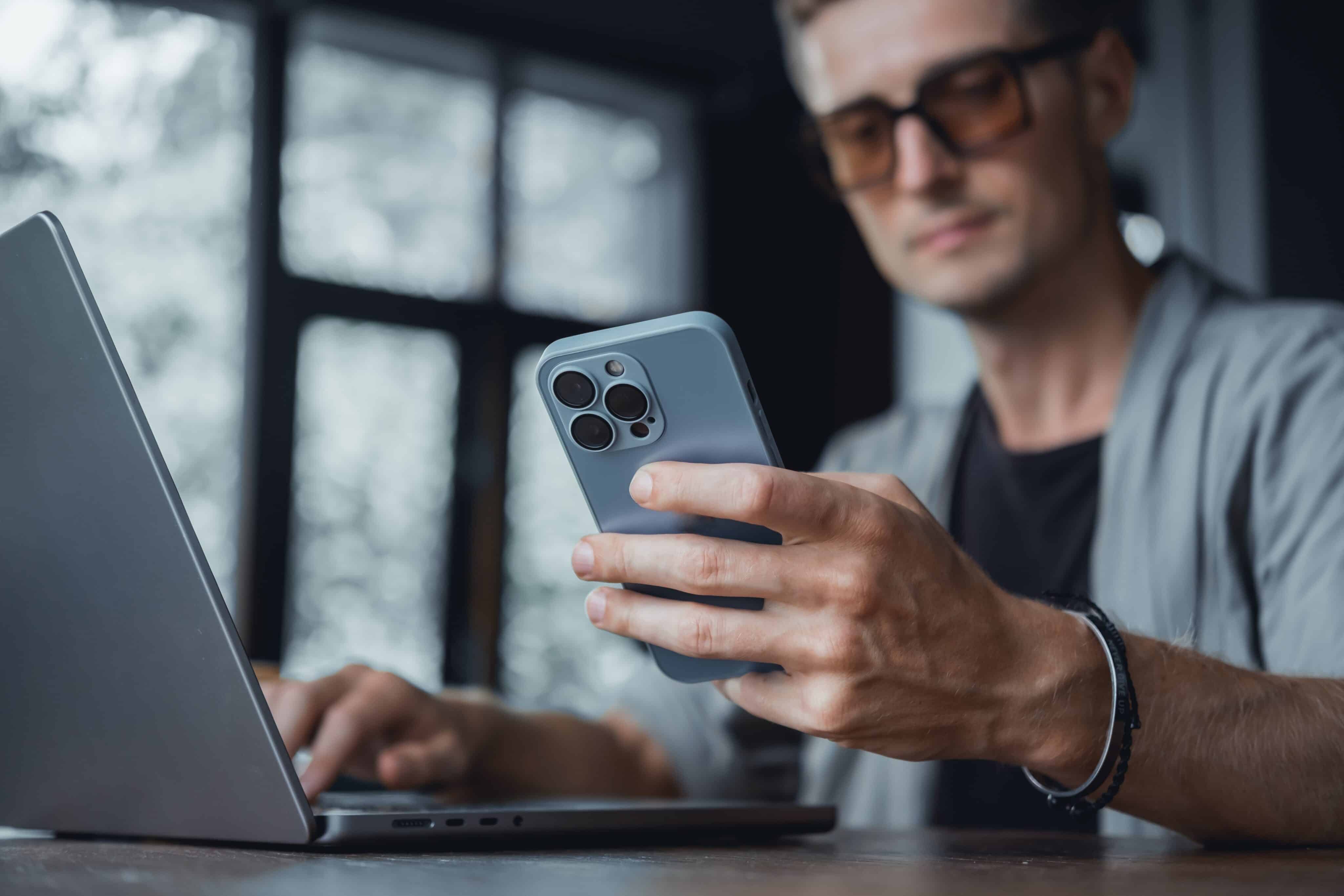 Hombre usando una MacBook Pro y un iPhone