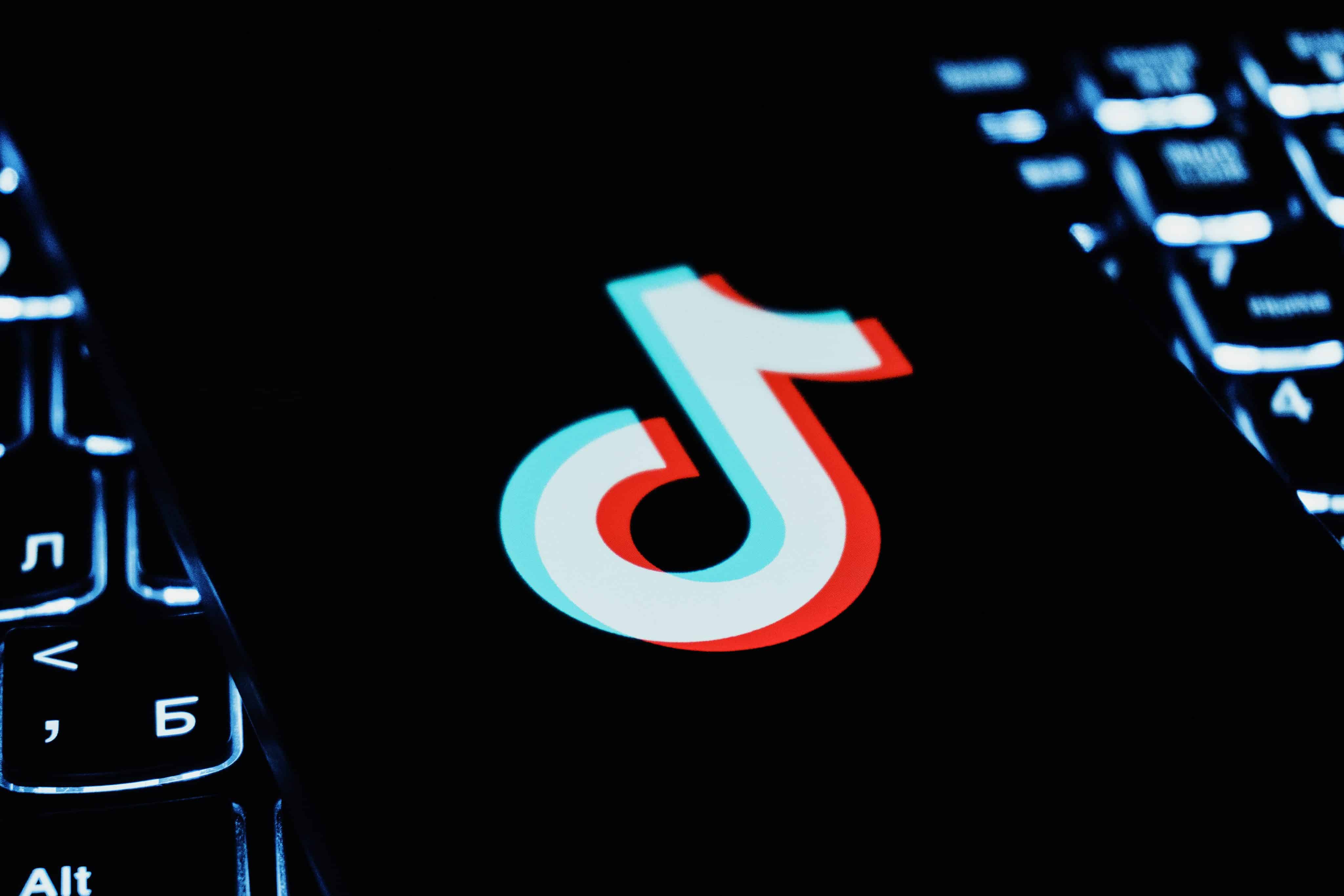 Logotipo de TikTok en un teléfono que está encima del teclado de una computadora portátil